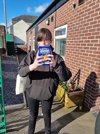 Person holding pack of Jaffa Cakes outside house.