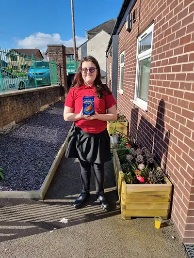 Person holds Easter egg gift outside brick building.