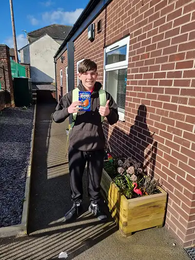 Person holding a book, standing outside building