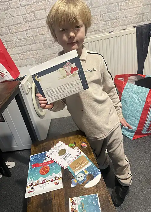 Child holding Christmas-themed letter and cards.